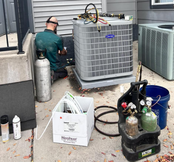 Webb's Electric, Heating & Air HVAC technician installing a new air conditioner in Pottsboro at a grey house.