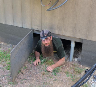 A Webb's Electric, Heating & Air technician crawling out of a Whitesboro crawlspace while maintaining a furnace.